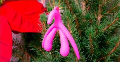 A pink clitoris model hanging from a Christmas Tree.